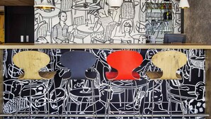 Una zona de bar con un mural en blanco y negro, una barra con vitrina de vidrio y un área de asientos con diseño original.