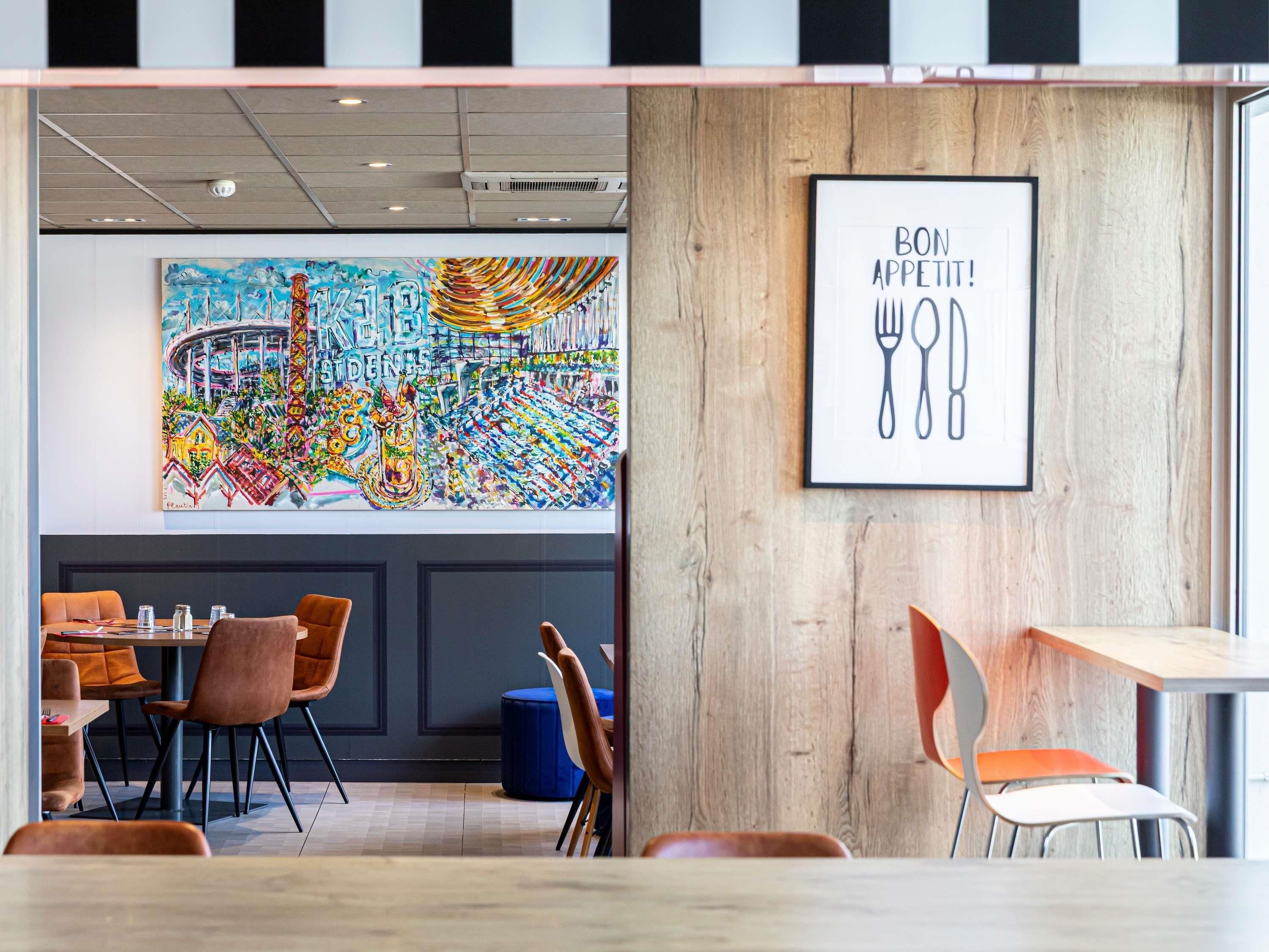 L’intérieur d’un restaurant est agrémenté d’une fresque murale colorée, de lambris en bois et d’une enseigne encadrée au-dessus du comptoir.