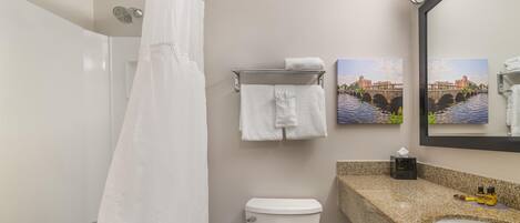 A bathroom with a shower, toilet, sink, and towel rack.