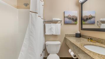 A bathroom with a shower, toilet, sink, and towel rack.
