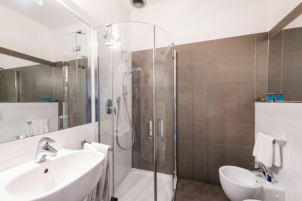 A modern bathroom with a glass-enclosed shower, a sink, and a bidet.
