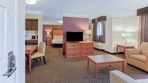 Een hotelkamer met een bed, een televisie, een bureau, een stoel, een bank en een kleine tafel.
