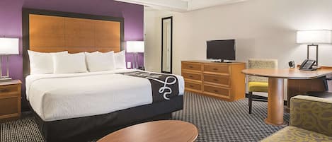 A hotel room with a bed, a desk, a chair, a television, and a telephone.