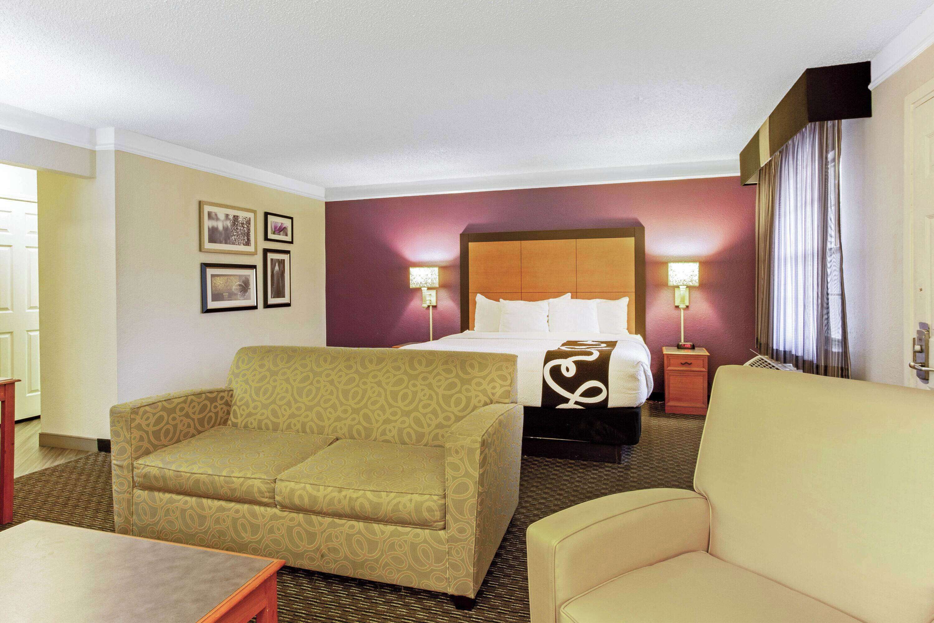Een hotelkamer met een bed, twee slaapbanken, een nachtkastje en een lamp.