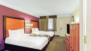 Habitación de hotel con dos camas, un aparador, televisor y ventana con cortinas.