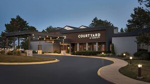 A Courtyard by Marriott hotel with a covered entrance, landscaped garden, and a curved driveway.