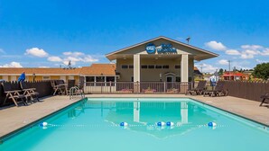 Una piscina con sillas de descanso y un edificio con el rótulo "Best Western" al fondo.