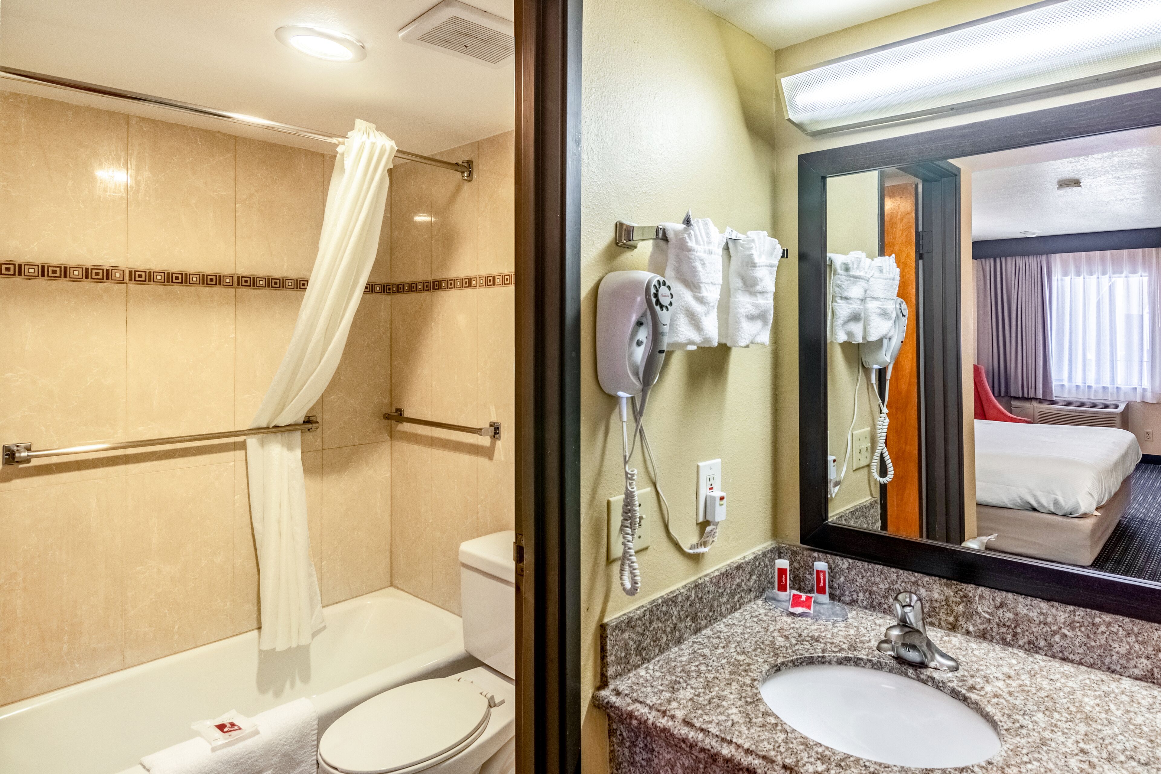 Un baño con ducha, inodoro y tocador con lavabo y espejo.