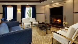 A modern living room with a sofa, armchairs, a coffee table, and a fireplace.