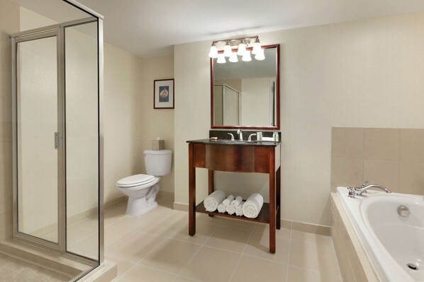 A bathroom with a glass-enclosed shower, a toilet, a sink with a mirror, and a bathtub.