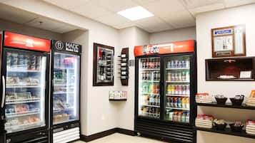 Una tienda de conveniencia con dispensadores de bebidas frías, estantes llenos de bocadillos y un refrigerador de Coca-Cola.