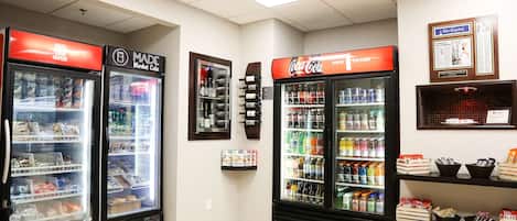 Una tienda de conveniencia con dispensadores de bebidas frías, estantes llenos de bocadillos y un refrigerador de Coca-Cola.