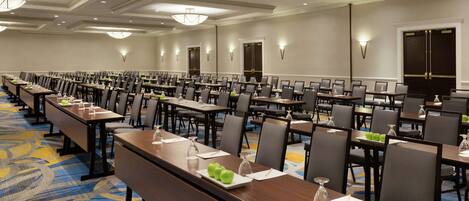 A large conference room with long tables and chairs, equipped with nameplates and water bottles.