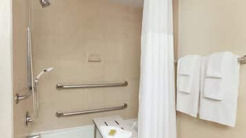Baño con ducha, barras de apoyo, toallero y portarrollo de papel higiénico.