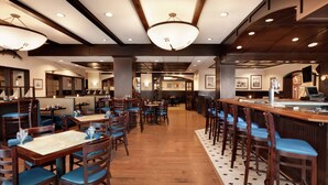 A restaurant with wooden tables and chairs, a bar area, and a tiled floor.