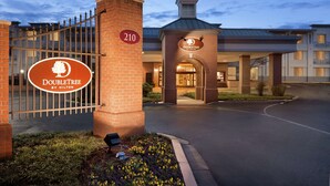 A DoubleTree by Hilton hotel entrance with a brick facade, a gated driveway, and a clear sky.