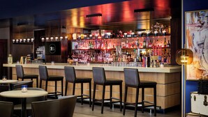 A bar area with a counter, bar stools, and a variety of bottles.