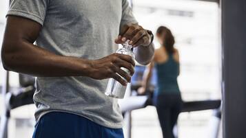 A person in a gym, holding a water bottle.