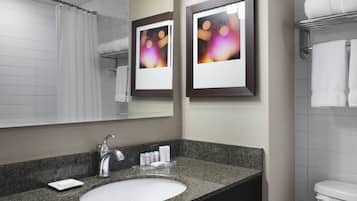 A bathroom with a granite countertop sink, a mirror, framed pictures, and a towel rack.