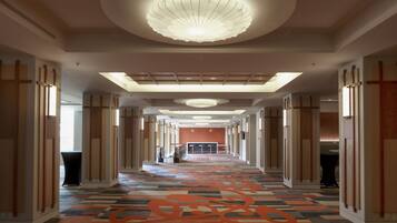 Un pasillo de hotel con alfombra estampada, paneles de madera y una lámpara central.