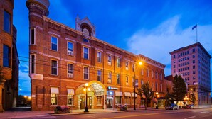 A historic brick building with a prominent corner entrance, a clock tower, and a large arched window. - Best Western Park Hotel (Warren)