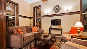 A living room with a sofa, armchair, coffee table, and a TV. - Best Western Park Hotel (Warren)
