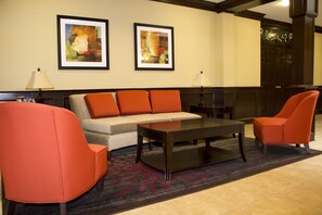 A hotel lobby with a sofa, two armchairs, a coffee table, and two lamps. There are two framed pictures on the wall. - Best Western Park Hotel (Warren)