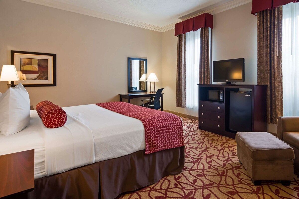 A hotel room with a bed, a desk, a television, and a chair.