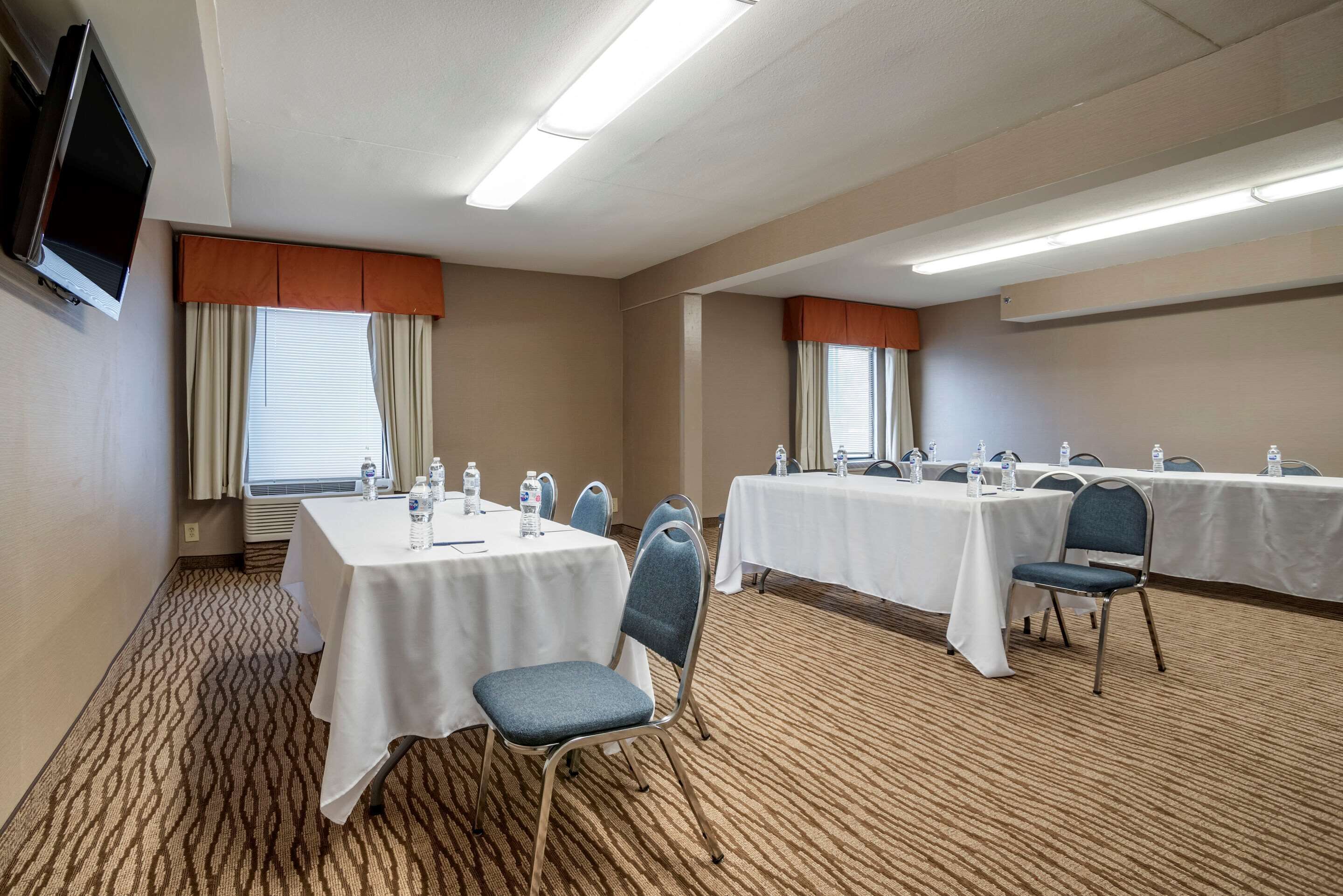 A conference room with two tables, chairs, and a television.