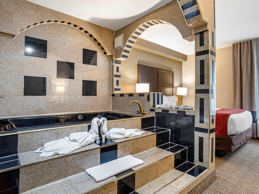 Un baño de hotel moderno con una bañera grande, un tocador con espejo y una zona de ducha independiente.