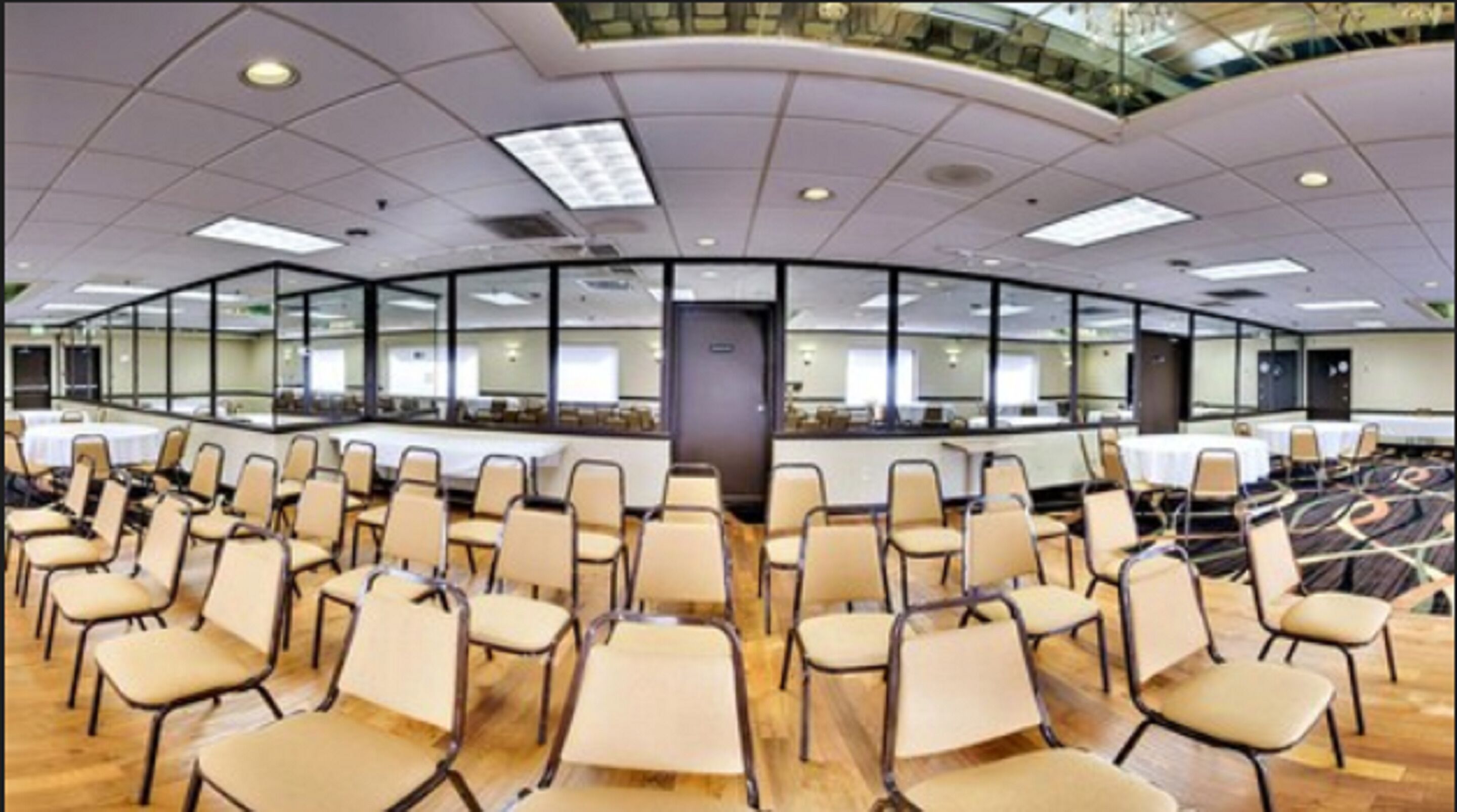 A conference room with rows of chairs, a large table, and a glass wall.