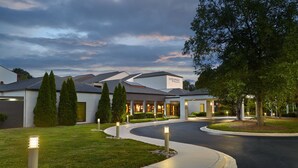 A hotel with a modern design, featuring a curved driveway and well-maintained landscaping. - Courtyard Charlotte Arrowood (Charlotte)