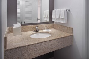 A bathroom with a granite countertop sink, a mirror, and a towel rack with white towels. - Courtyard Charlotte Arrowood (Charlotte)