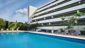 Un hôtel moderne doté d’une piscine, d’un espace extérieur aménagé et d’une façade végétalisée.
