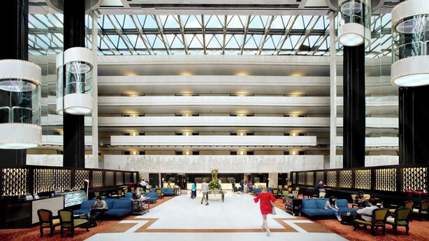 Un hall d’entrée spacieux comprenant plusieurs espaces de détente, un comptoir d’accueil et un élément décoratif central.