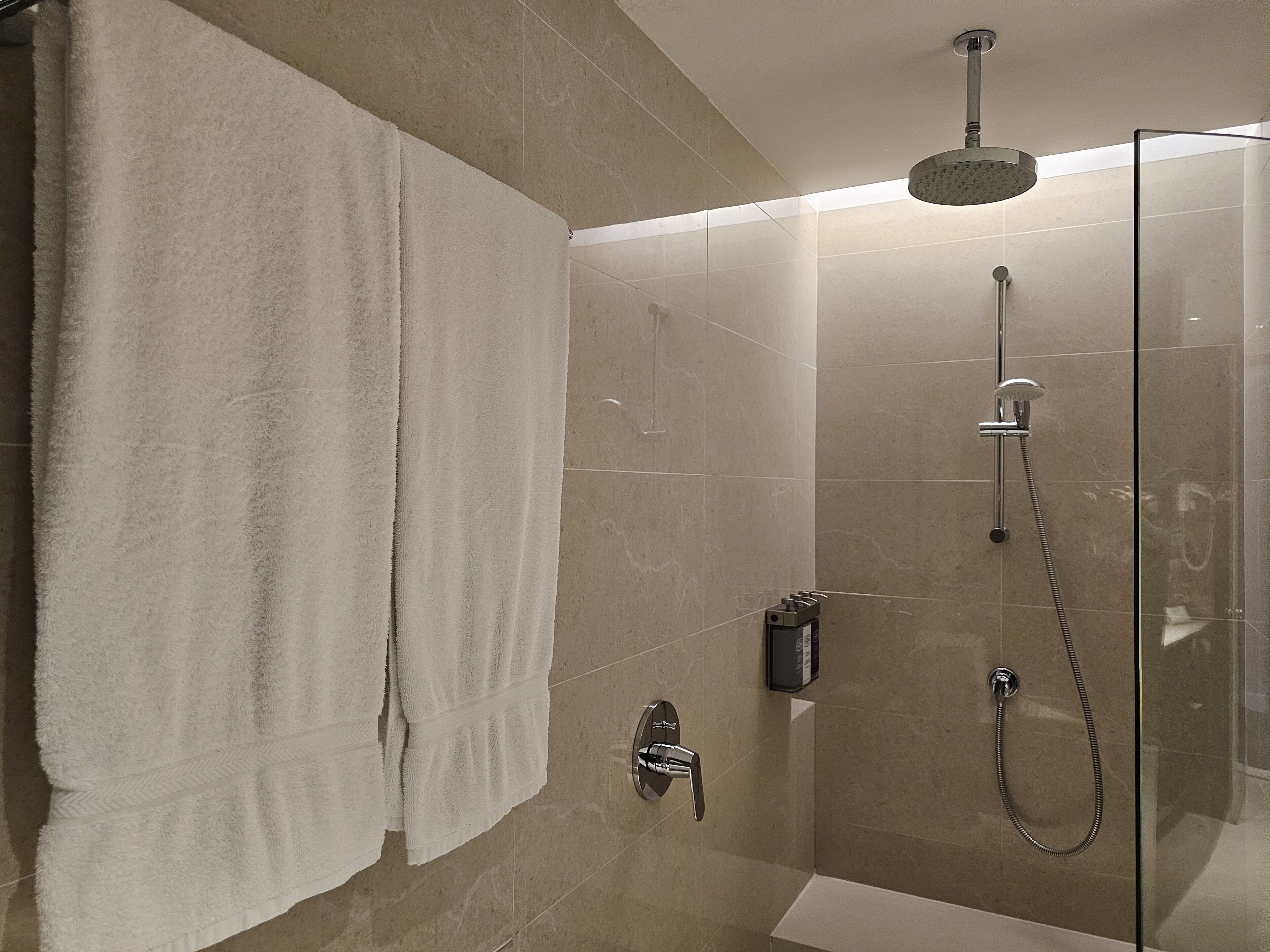 A modern shower area with a glass enclosure, a handheld showerhead, and a wall-mounted faucet.