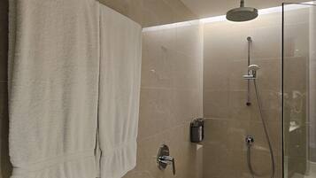 A modern shower area with a glass enclosure, a handheld showerhead, and a wall-mounted faucet.