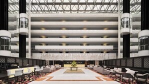 Un hall d’hôtel à plusieurs niveaux, doté d’un espace salon central, de nombreux étages et d’un design moderne.
