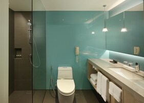 A modern bathroom with a glass shower enclosure, a toilet, a sink with a mirror, and a towel rack.