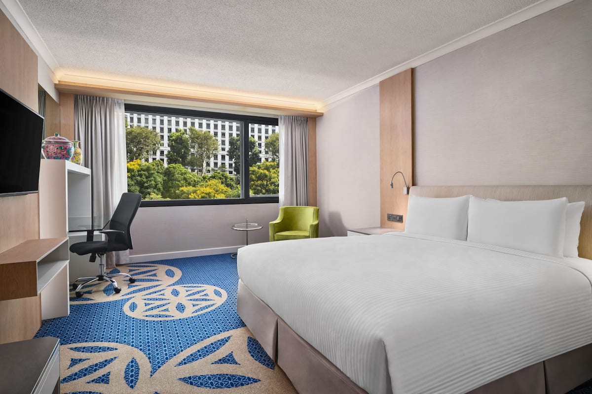 A hotel room with a large bed, a desk, a chair, and a television.