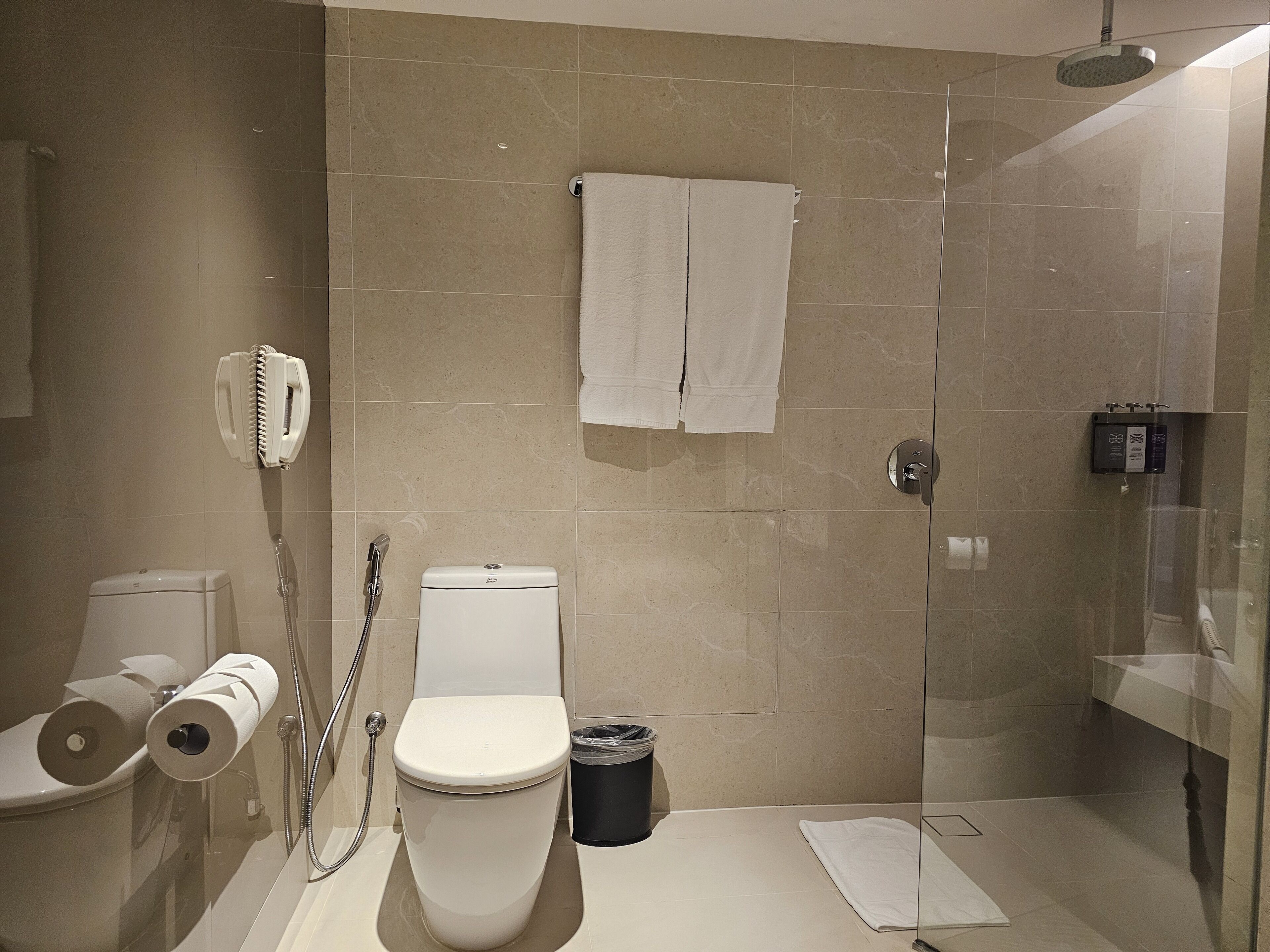 Un baño moderno con inodoro, bidé y ducha con cerramiento de vidrio.