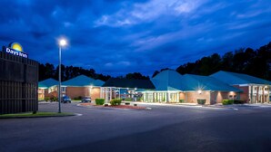 A Days Inn with a large parking lot, multiple buildings with blue roofs, and a well-lit entrance. - Days Inn by Wyndham Petersburg/South Fort Lee (Petersburg)