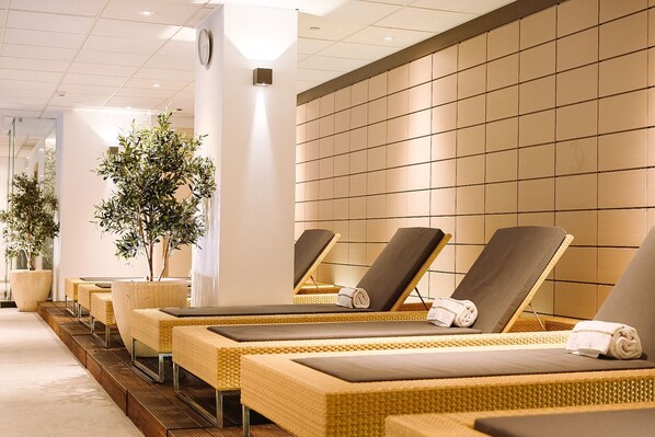 A spa area with reclining chairs, potted plants, and a tiled wall. - Steigenberger Icon Wiltcher's (Brussels)
