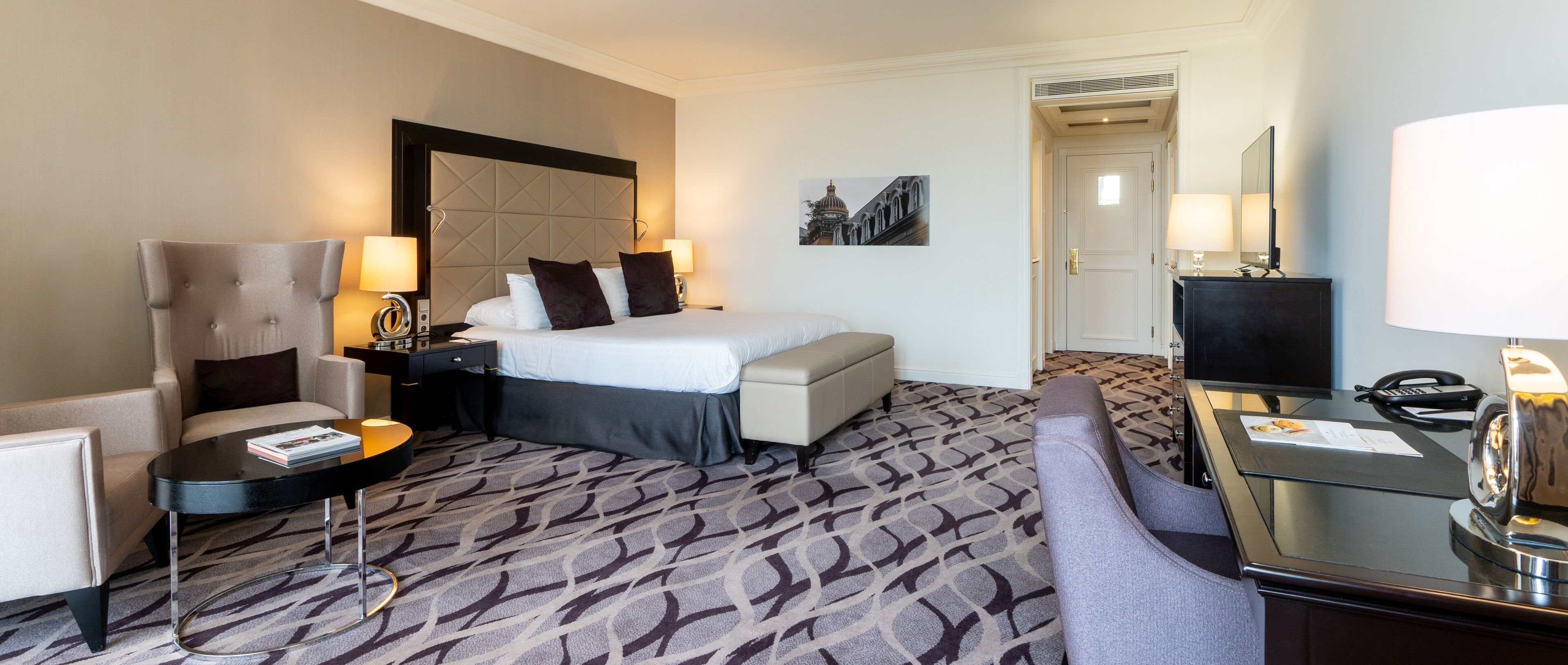 Een hotelkamer met een bed, een stoel, een bureau en een televisie.
