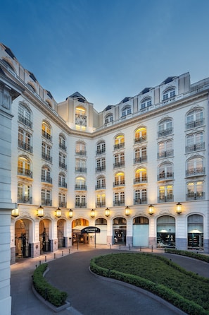 Un edificio grande e histórico con varios pisos, ventanas en arco y una entrada central con un letrero.