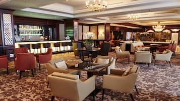 A spacious lobby with a bar area, multiple seating arrangements, and decorative lighting fixtures.