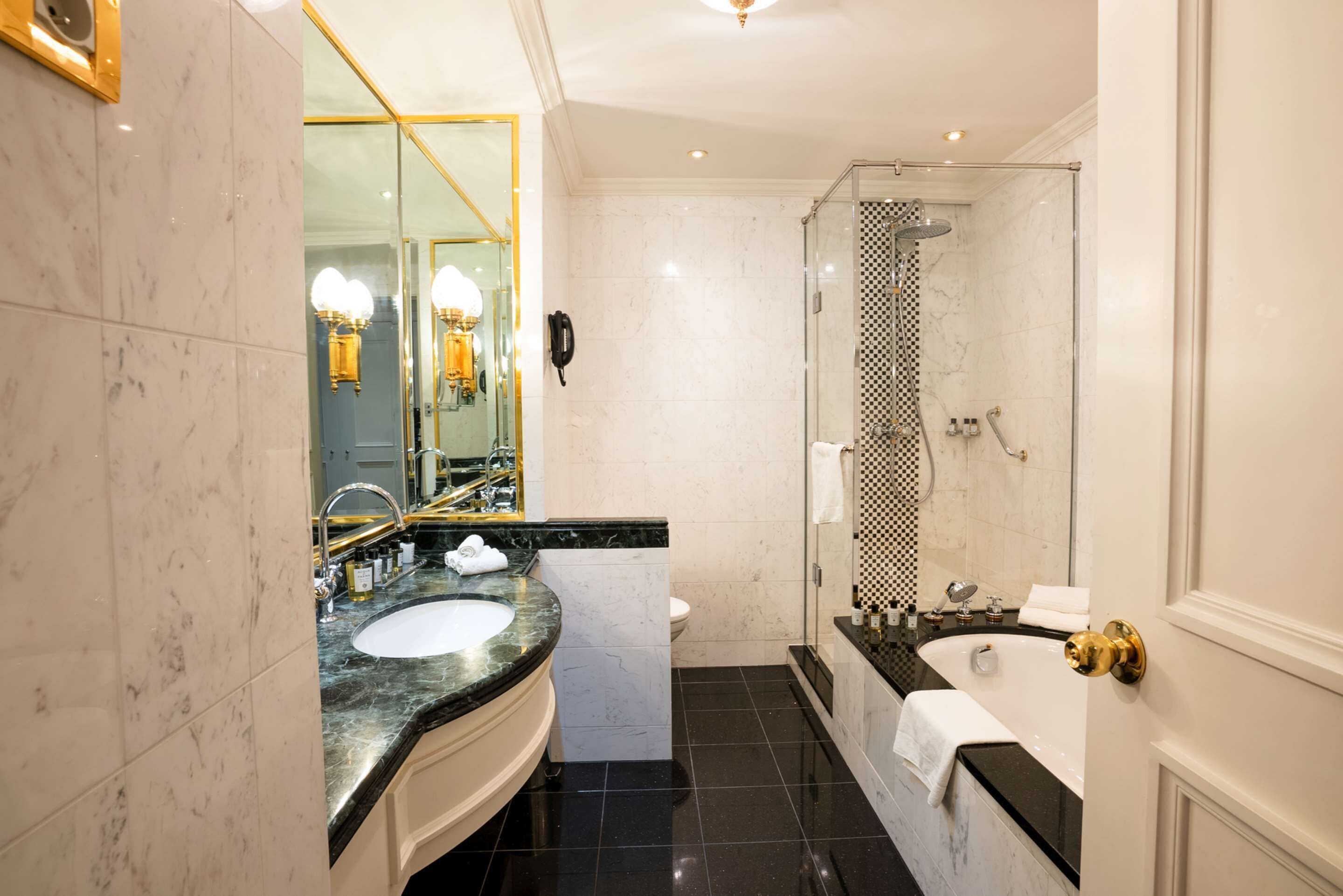 Un baño moderno con un lavabo de mármol, ducha con cerramiento de vidrio y un espejo grande.