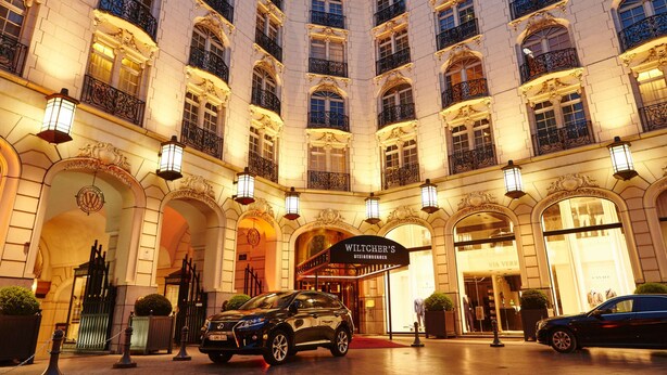Un hotel elegante con un patio central, balcones ornamentados y un letrero que dice 'WILCHER'S'.