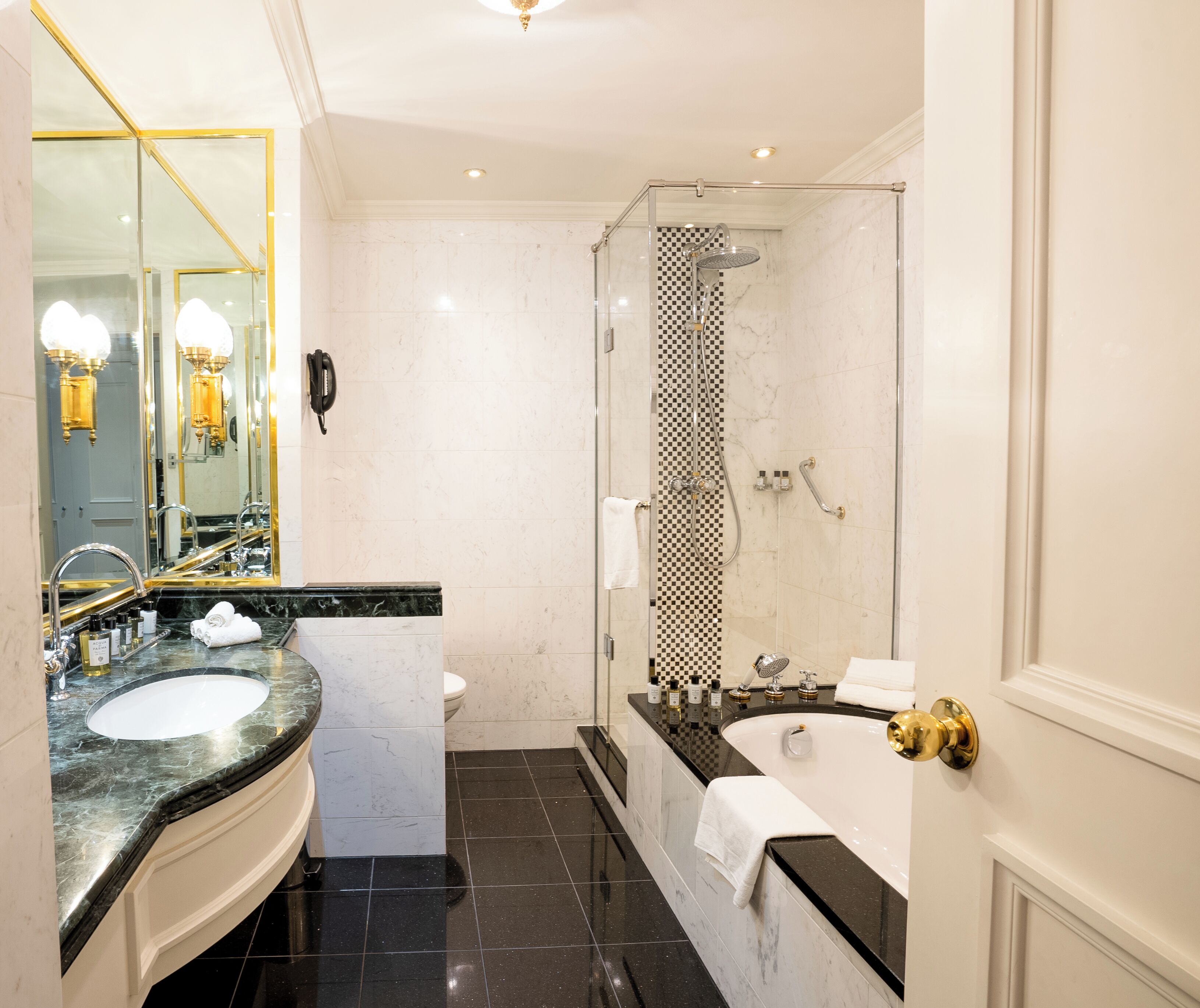 Un baño moderno con un espejo grande, dos lavamanos, un inodoro, una ducha con puerta de cristal y una bañera.