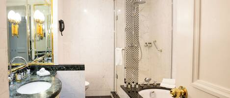Un baño moderno con un espejo grande, dos lavamanos, un inodoro, una ducha con puerta de cristal y una bañera.